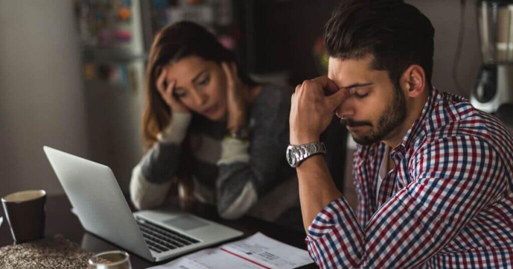 A couple addressing debt while working at a desk with a laptop.