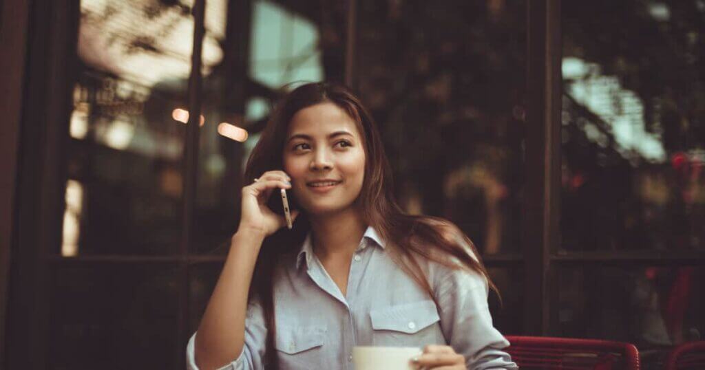 A woman sitting at a table using the Scotia Momentum card and talking on the phone.
