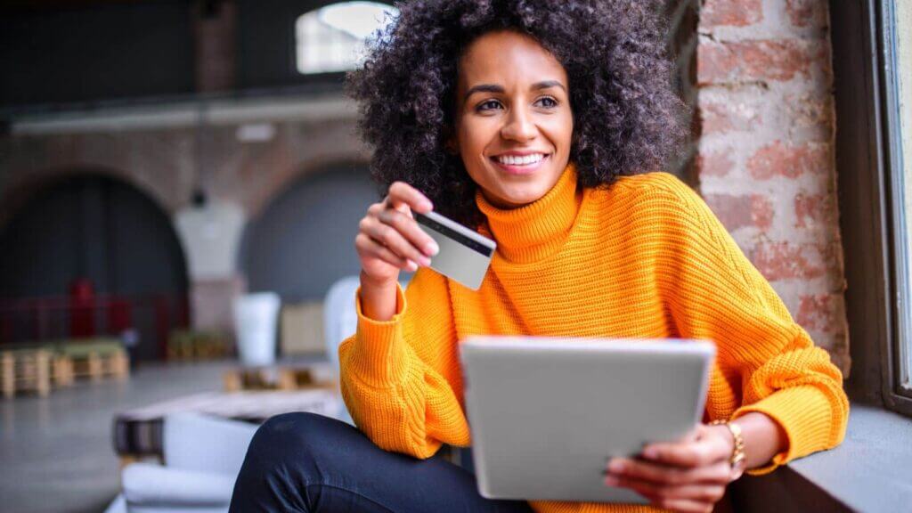 A woman holding a BMO Bank credit card while sitting.